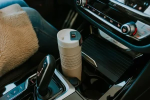 Termoláhev Kambukka Etna Grip v držáku na nápoje v autě vedle řadicí páky